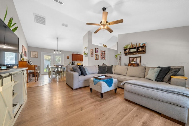 living room featuring ceiling fan with notable chandelier, light wood-style floors, and visible vents