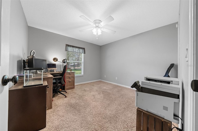 office space with baseboards, light colored carpet, a ceiling fan, and a textured ceiling