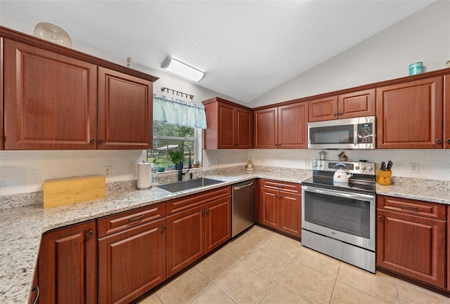 kitchen featuring light tile patterned floors, lofted ceiling, a sink, appliances with stainless steel finishes, and a textured ceiling