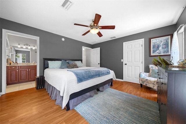 bedroom featuring ensuite bath, light wood-style floors, and visible vents