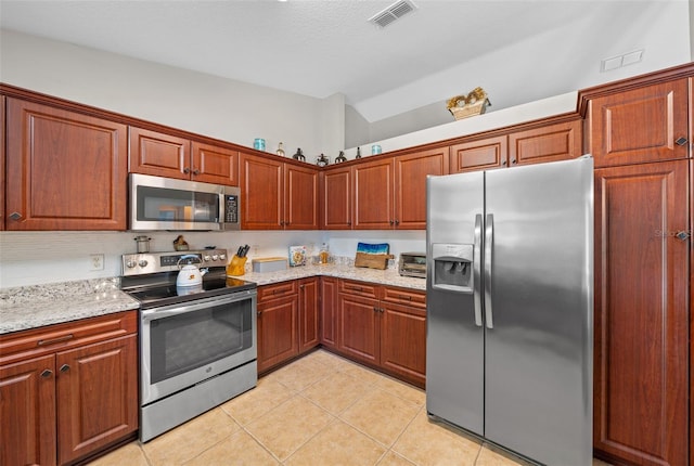 kitchen with light tile patterned floors, stainless steel appliances, light stone counters, and visible vents