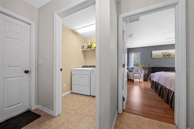 interior space with laundry area, light tile patterned floors, visible vents, and a textured ceiling