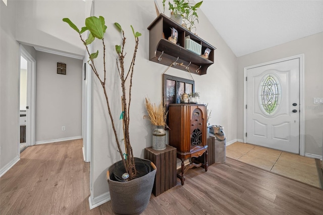 entrance foyer with vaulted ceiling, baseboards, and wood finished floors