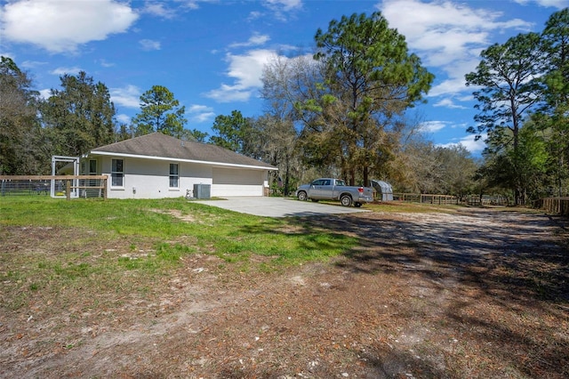 view of yard featuring cooling unit, concrete driveway, and fence