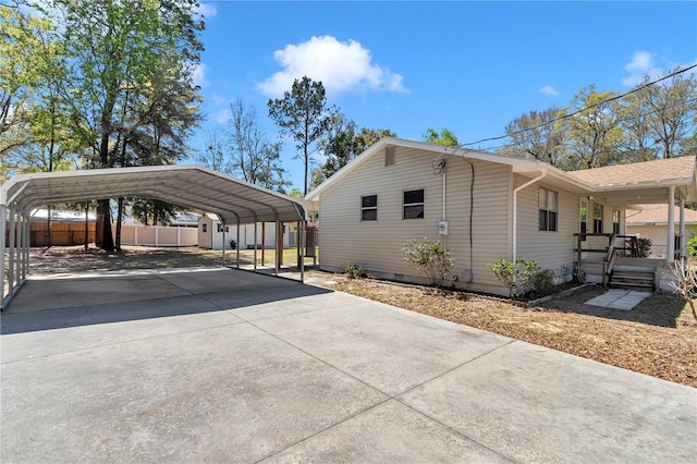 view of property exterior with a carport, concrete driveway, and fence