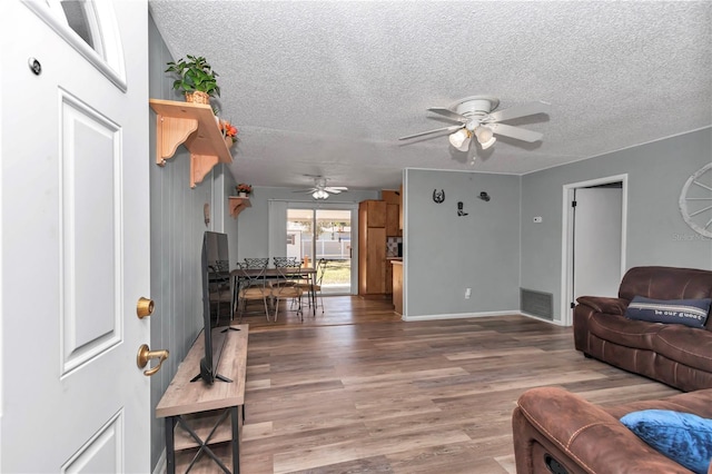 living area with ceiling fan, visible vents, a textured ceiling, and wood finished floors