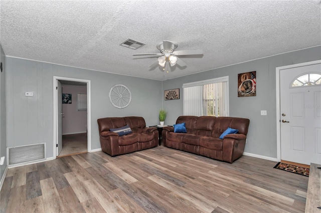 living area with a ceiling fan, wood finished floors, and visible vents