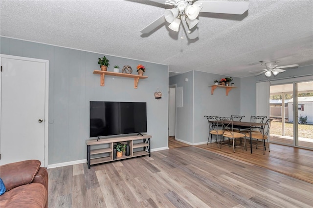 living area with baseboards, a textured ceiling, ceiling fan, and wood finished floors