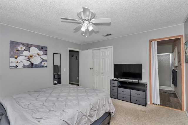 carpeted bedroom with a closet, visible vents, a textured ceiling, and a ceiling fan