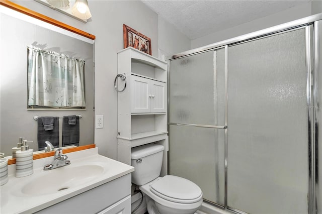 full bath featuring vanity, toilet, a stall shower, and a textured ceiling