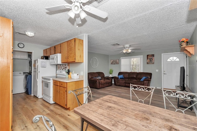 kitchen with light wood-type flooring, light countertops, washer / dryer, white appliances, and a ceiling fan