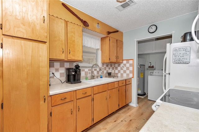 kitchen with light countertops, decorative backsplash, light wood-style floors, washer / clothes dryer, and a sink