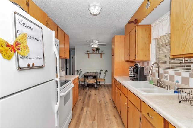 kitchen featuring white appliances, light wood-style flooring, a sink, light countertops, and a textured ceiling