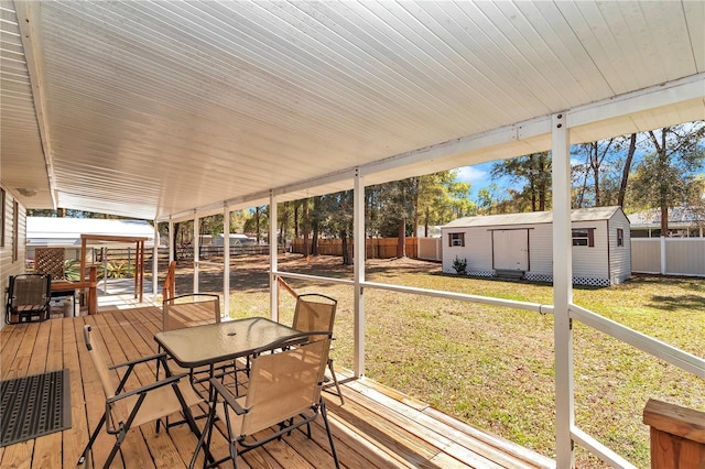 wooden deck with an outbuilding, outdoor dining space, a lawn, and a fenced backyard