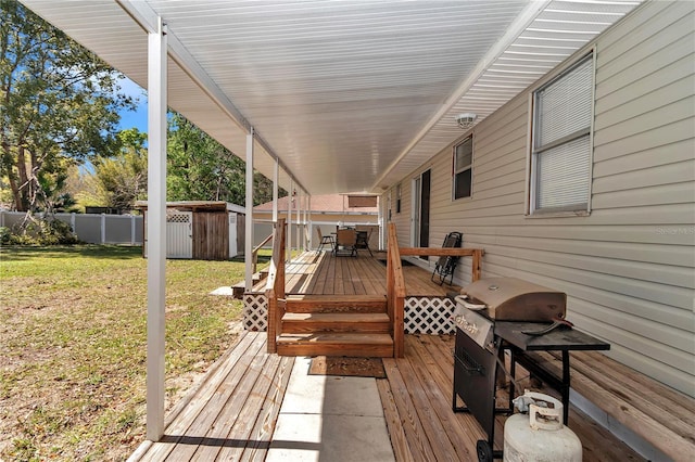 wooden terrace with a shed, a lawn, a fenced backyard, an outdoor structure, and outdoor dining space