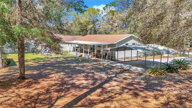 exterior space with a front yard, a detached carport, and dirt driveway