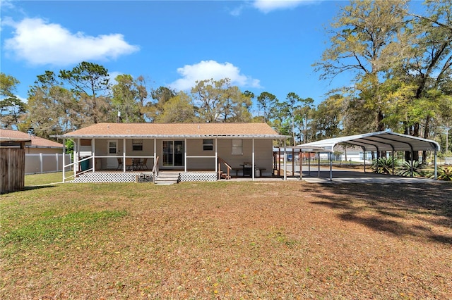 back of house featuring entry steps, a detached carport, fence, and a lawn