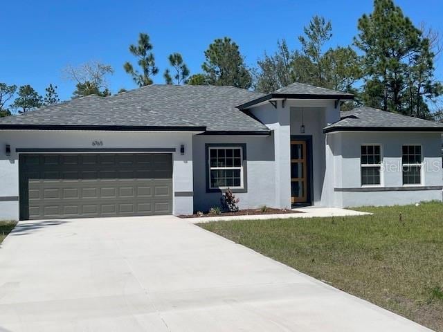 view of front of property featuring stucco siding, driveway, a front yard, and an attached garage