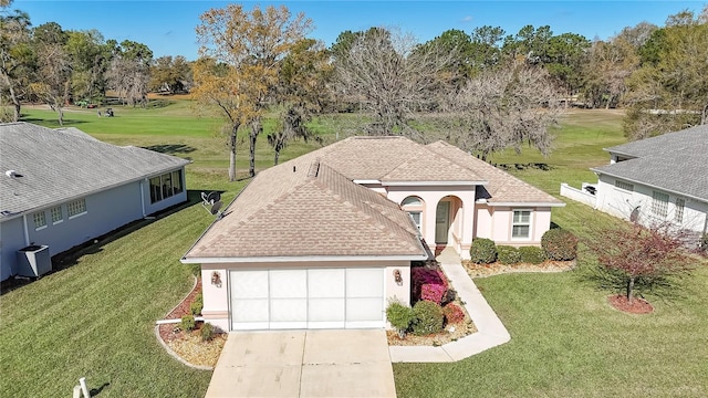 view of front of home featuring stucco siding, cooling unit, concrete driveway, an attached garage, and a front yard