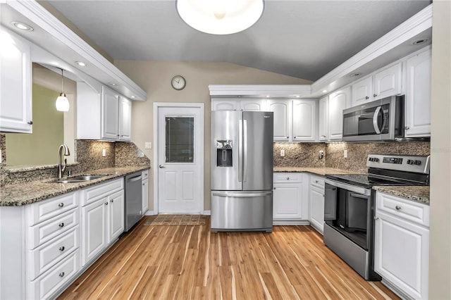 kitchen with a sink, white cabinetry, stainless steel appliances, light wood-style floors, and lofted ceiling