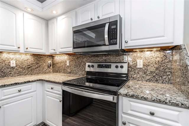 kitchen with decorative backsplash, white cabinetry, stainless steel appliances, and light stone countertops