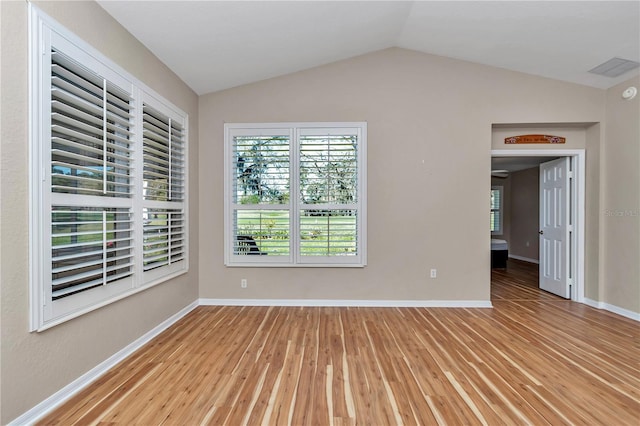 unfurnished room featuring baseboards, lofted ceiling, and wood finished floors