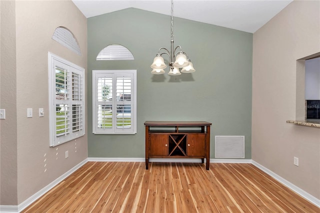 unfurnished dining area featuring baseboards, wood finished floors, visible vents, and a chandelier