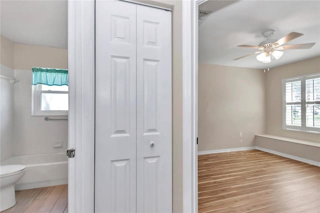 full bathroom with baseboards, ceiling fan, toilet, wood finished floors, and a closet