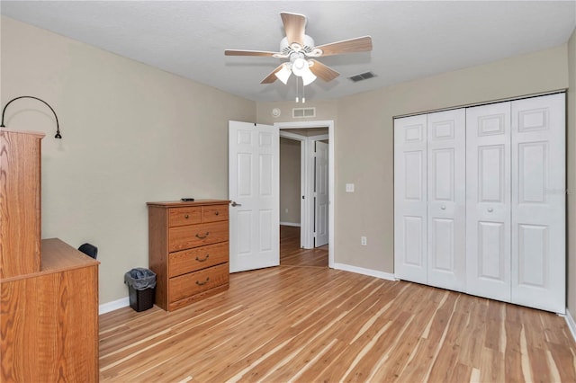 unfurnished bedroom with a closet, baseboards, visible vents, and light wood finished floors