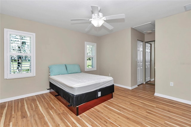 bedroom with multiple windows, light wood-style flooring, and baseboards