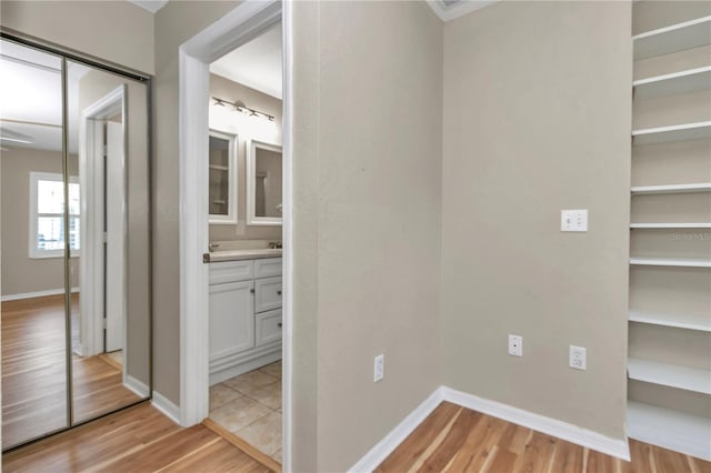 corridor featuring baseboards and light wood-style flooring