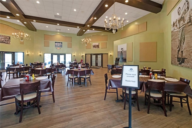 dining area featuring a chandelier, beamed ceiling, french doors, and wood finished floors