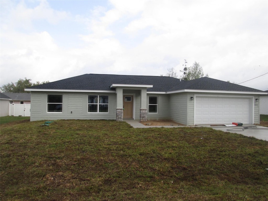 ranch-style home with an attached garage, concrete driveway, and a front yard