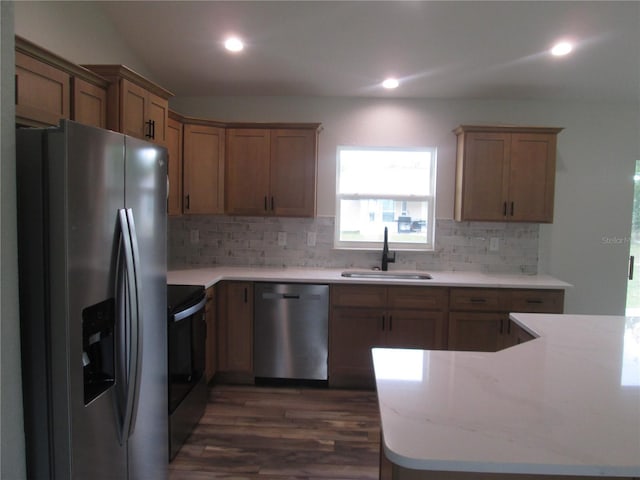 kitchen featuring decorative backsplash, dark wood-style flooring, light countertops, stainless steel appliances, and a sink
