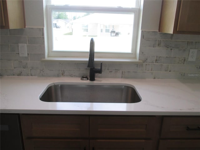 kitchen with decorative backsplash, light countertops, and a sink