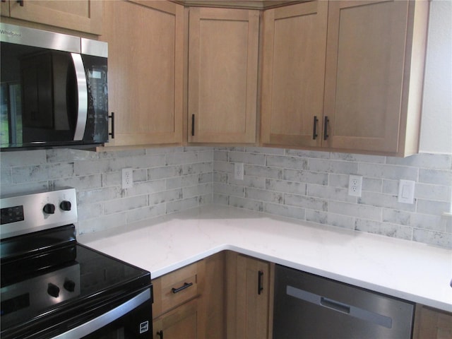 kitchen featuring decorative backsplash, light countertops, and appliances with stainless steel finishes