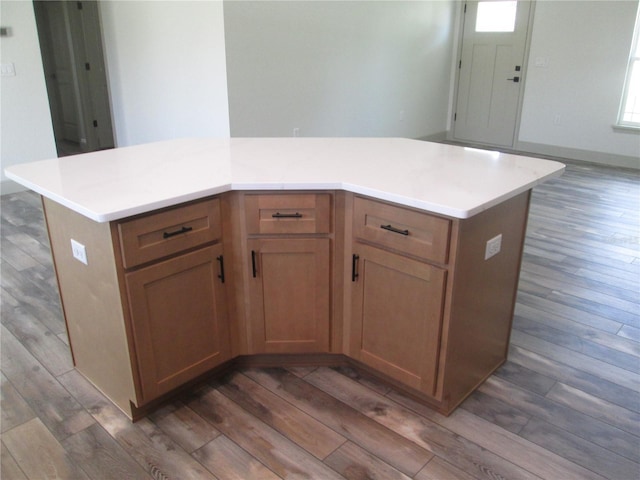 kitchen featuring dark wood-style floors, a center island, light countertops, and a wealth of natural light