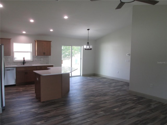 kitchen with backsplash, a kitchen island, a sink, dishwasher, and ceiling fan with notable chandelier