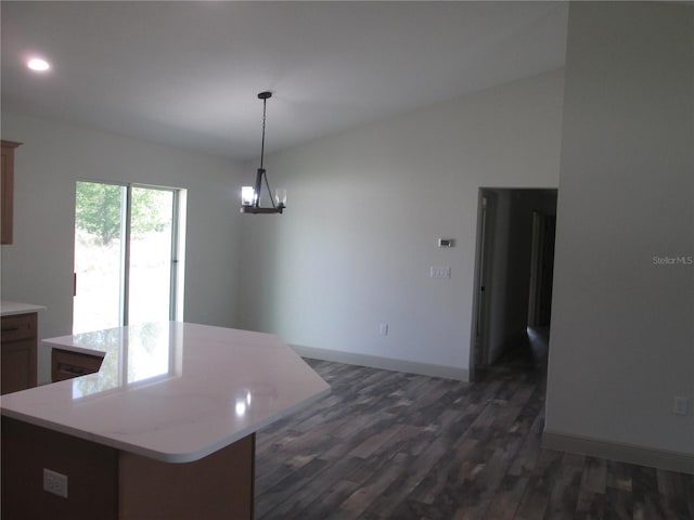kitchen with light countertops, dark wood-style flooring, a center island, and baseboards