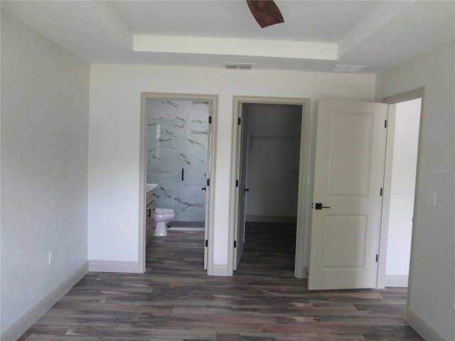 unfurnished bedroom with baseboards, visible vents, wood finished floors, and a raised ceiling