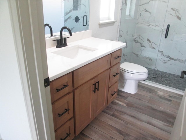full bath with a marble finish shower, wood finished floors, toilet, and vanity
