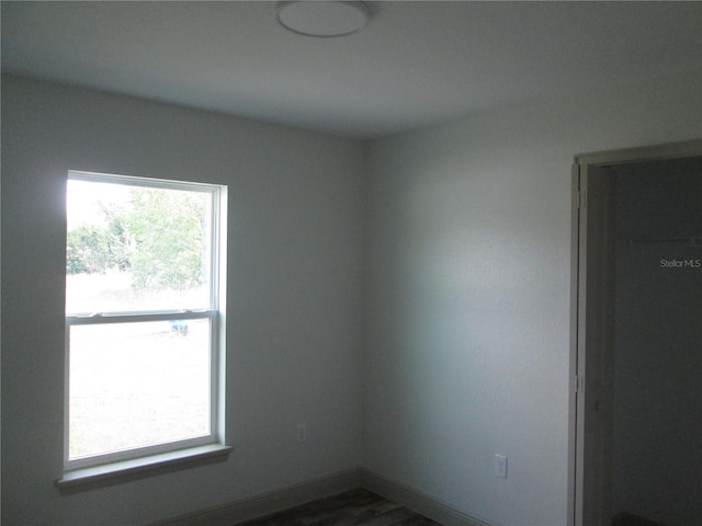 unfurnished room featuring baseboards and dark wood-type flooring