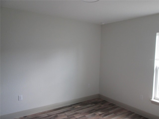 spare room featuring baseboards and wood finished floors