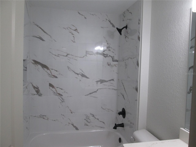 bathroom with  shower combination, toilet, and a textured wall