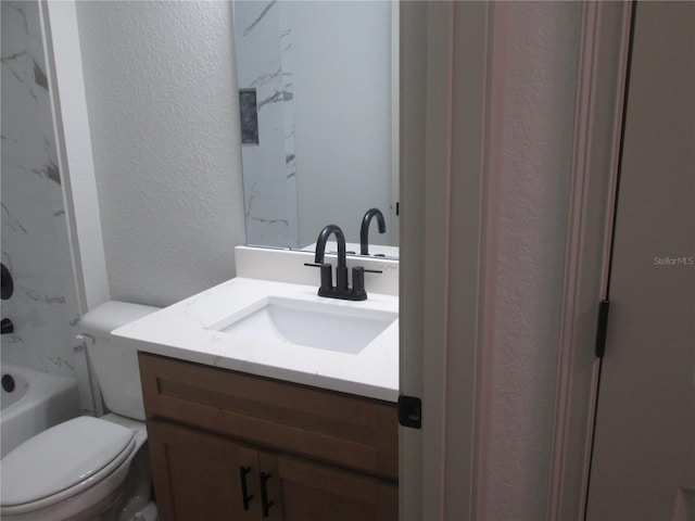 bathroom featuring toilet, vanity, a textured wall, and bathtub / shower combination