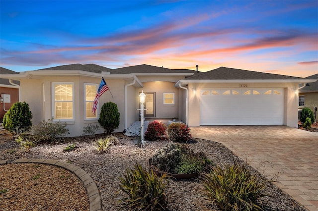 view of front of home with stucco siding, decorative driveway, and a garage