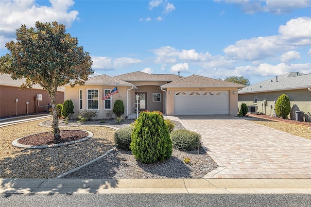 view of front facade featuring stucco siding, decorative driveway, and a garage