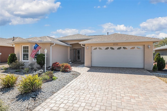 view of front facade with stucco siding, decorative driveway, and a garage