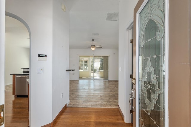 foyer with a ceiling fan, visible vents, wood finished floors, baseboards, and arched walkways