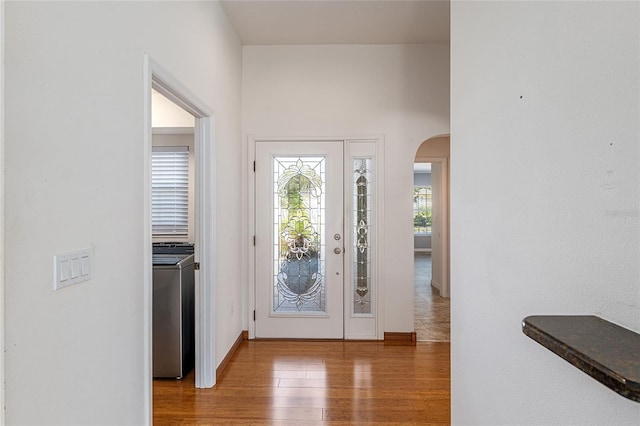 foyer entrance featuring arched walkways and wood finished floors